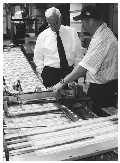 Former Treasury Secretary Paul O'Neil, left, looks at newly-printed bills with a Bureau of Printing employee during a tour of the Western Currency facility in Fort Worth, Texas. AP/WIDE WORLD PHOTOS.