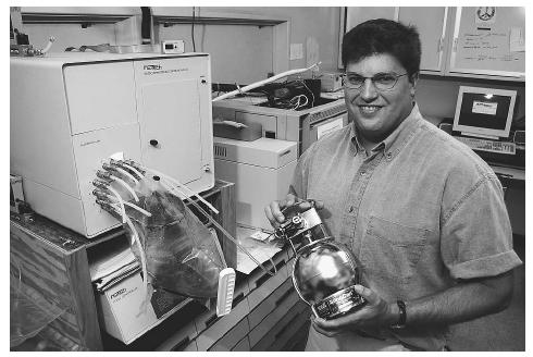 A researcher at the Environmental Technology Group at Pennsylvania State University holds a Suma canister, a device used to collect air samples, in front of a cryogenic concentrator and gas chromatograph that is used to analyze the sample. AP/WIDE WORLD PHOTOS.