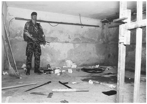 A British soldier stands in a room used for torture and interrogation in the Serbian military police headquarters in Pristina, 1999. Later, United Nations investigators examined the knives, wooden bats, brass knuckles, and drugs found in the building as part of a war crimes investigation. AP/WIDE WORLD PHOTOS.