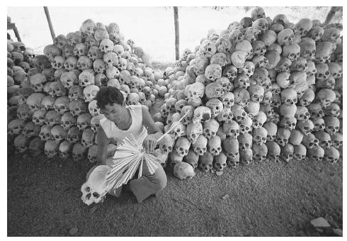 A man cleans, numbers, and stacks skulls near a mass grave at the Cheung Ek torture camp run by the Khmer Rouge in Cambodia, where Pol Pot tortured and murdered between one and two million people to eliminate perceived oppposition in the 1970s. AP/WIDE WORLD PHOTOS.