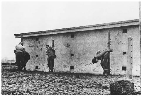 An American medical officer examines the bullet-riddled bodies of three German spies who died before a U.S. firing squad in Herbesthal, Belgium, in December 1944. ©BETTMANN/CORBIS.